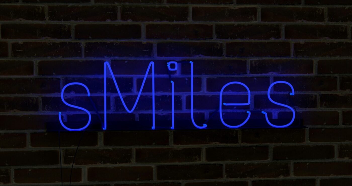 A blue neon sign glowing in daylight (Source: Unsplash - Mariia Shalabaieva) 